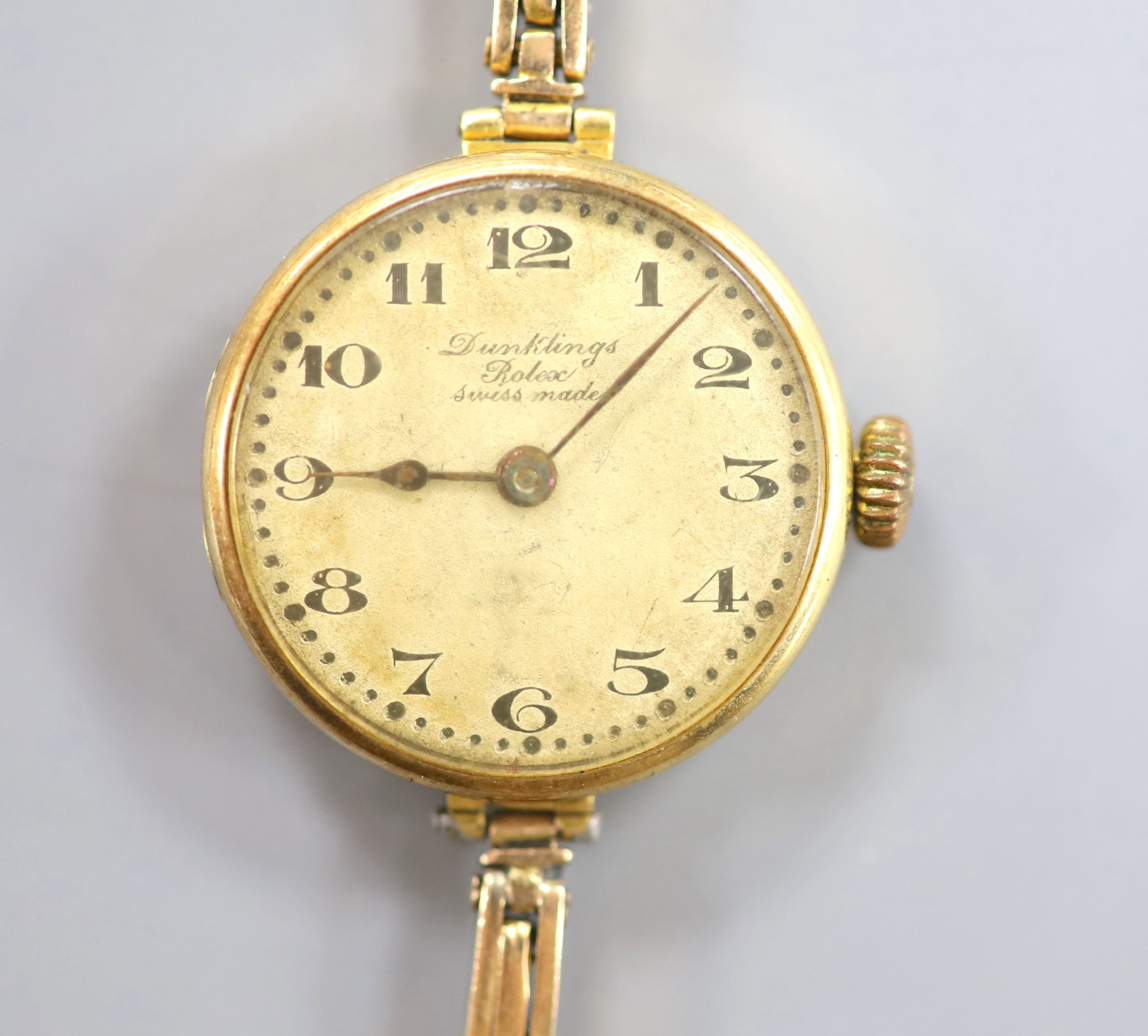 A lady's early 1920's 18ct gold Rolex manual wind wrist watch, with case back inscription, on a flexible yellow metal bracelet stamped 'W15D', case diameter 23mm, length 16.3cm, gross weight 20 grams.